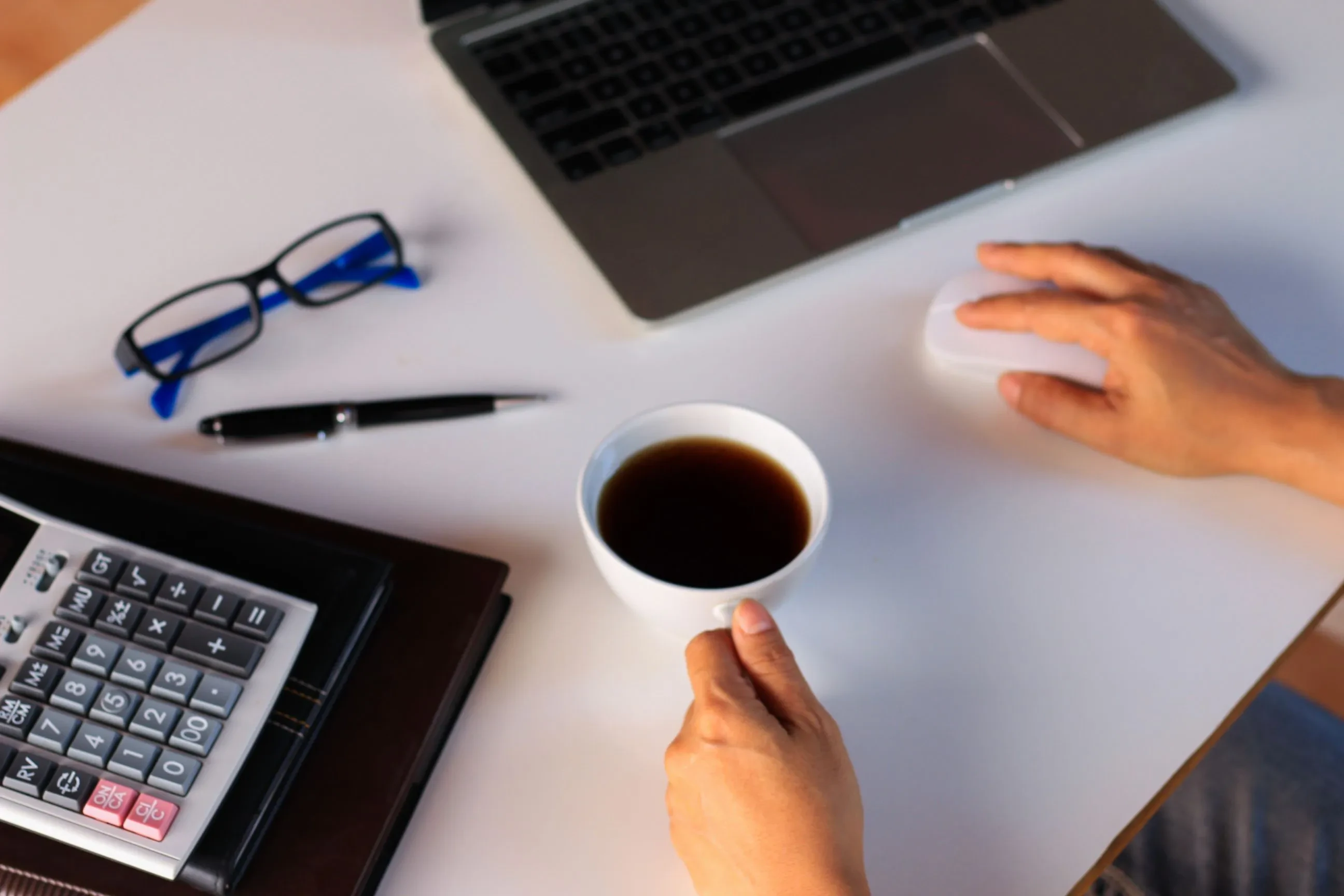 Workspace mit Laptop, Maus, Brille und Kaffee – Symbol für konzentriertes Arbeiten und digitale Projektsteuerung