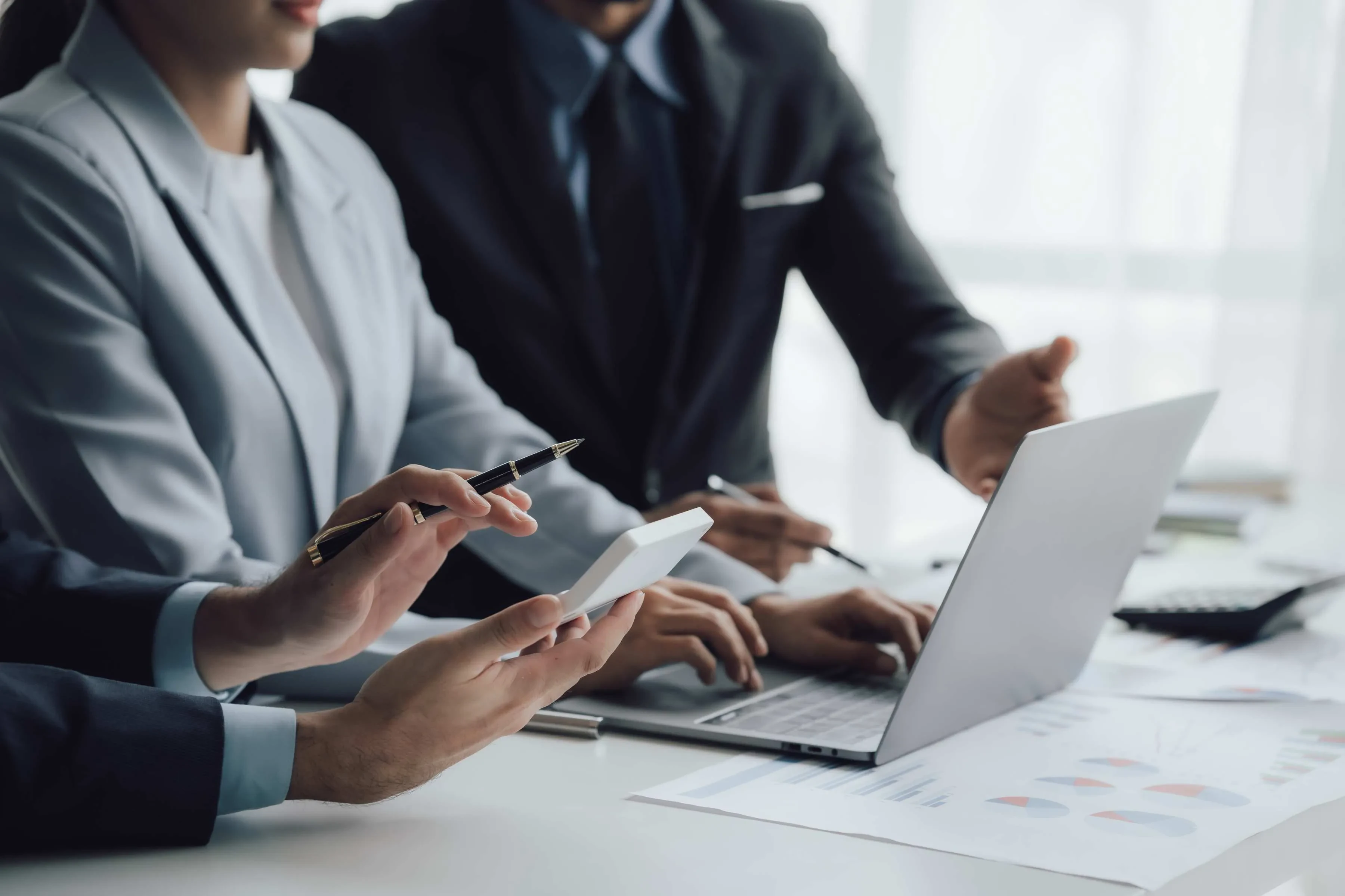 Gruppe im Meeting mit Laptop und Charts – Symbol für datenbasierte Teamarbeit und Projektabstimmung