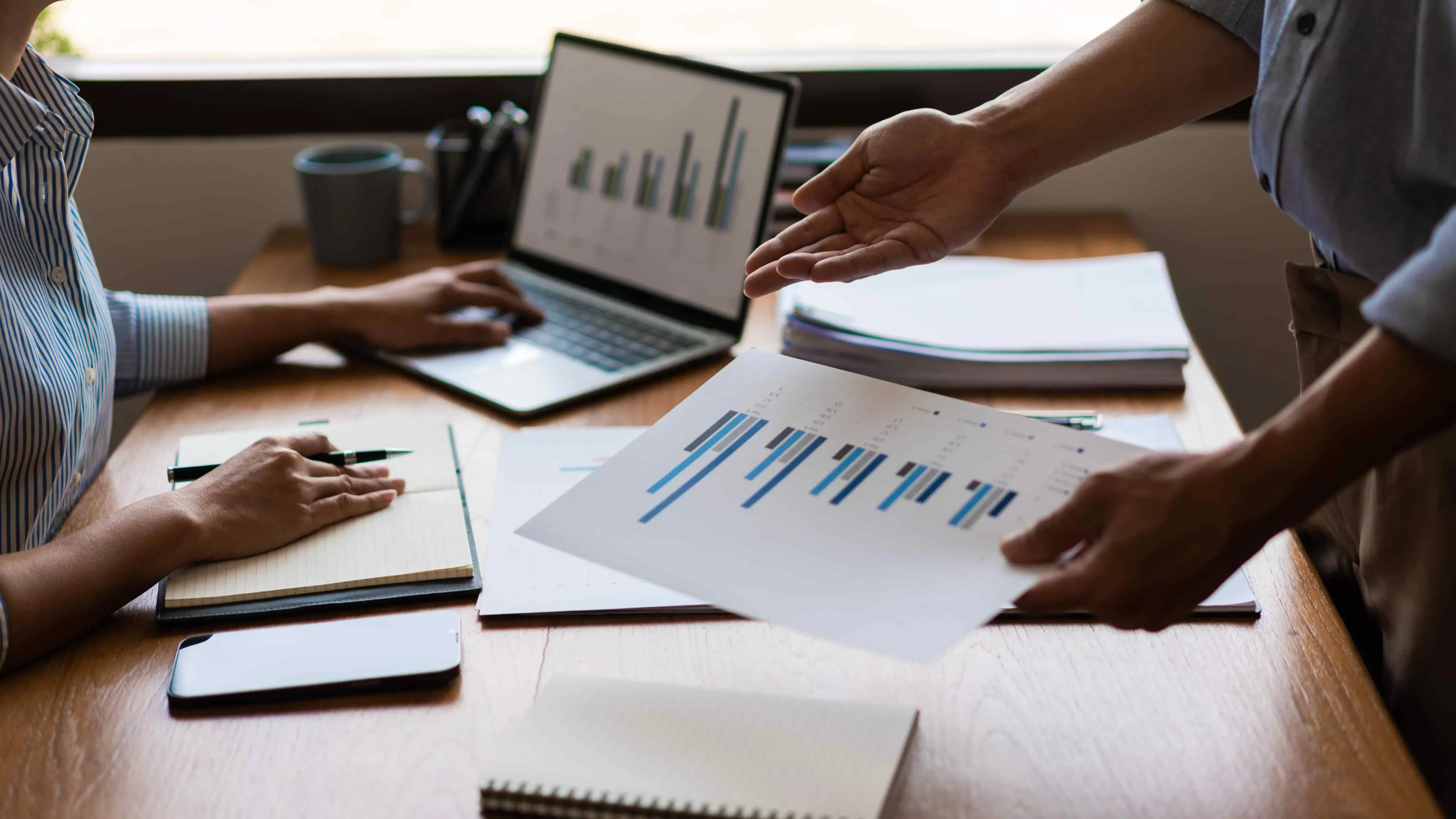 Zwei Personen mit Tablet und Charts im Gespräch – Symbol für datenbasierte Projektanalyse und digitale Zusammenarbeit