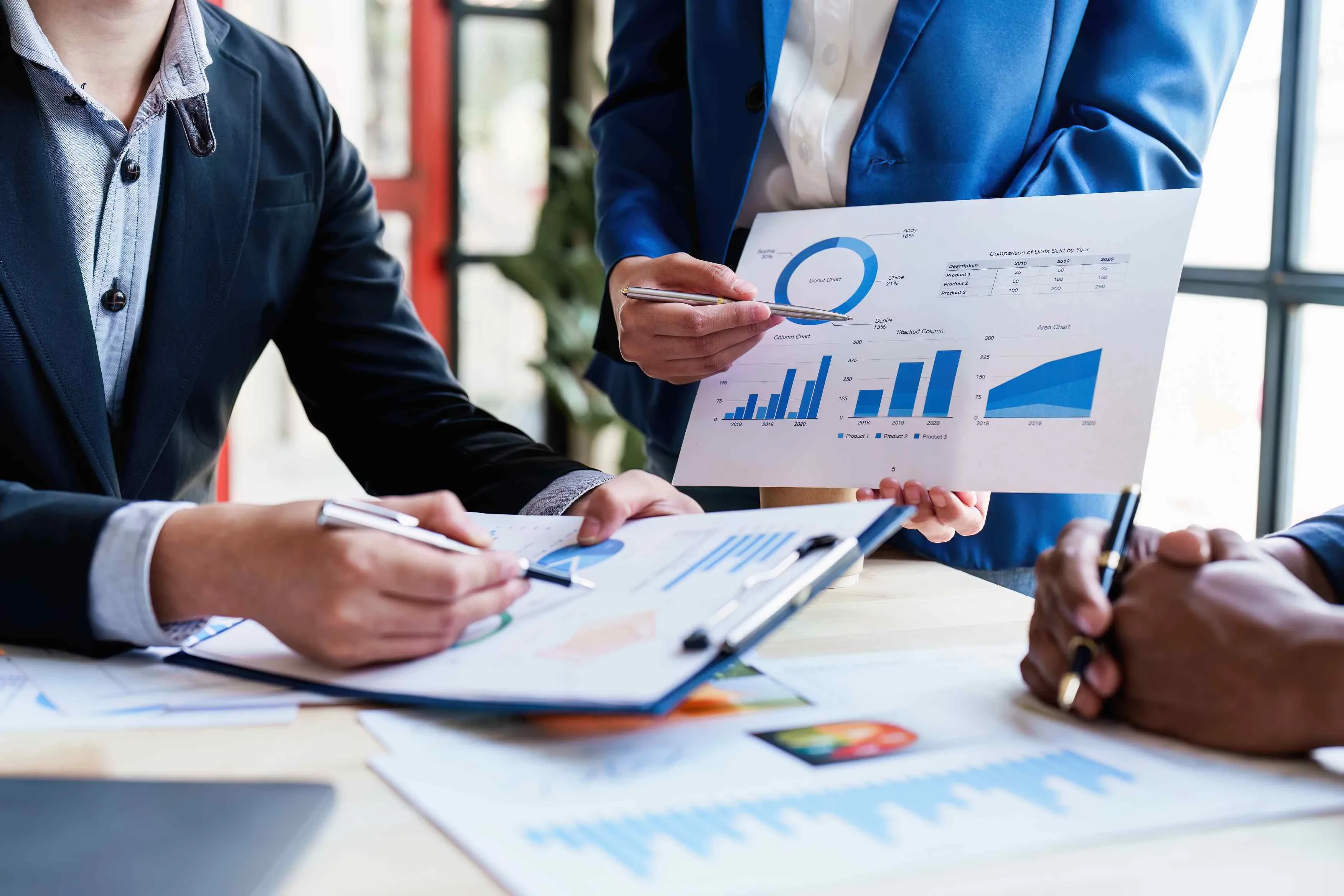 Drei Personen mit Charts im Meeting – Symbol für datenbasierte Teamarbeit und strategische Projektplanung