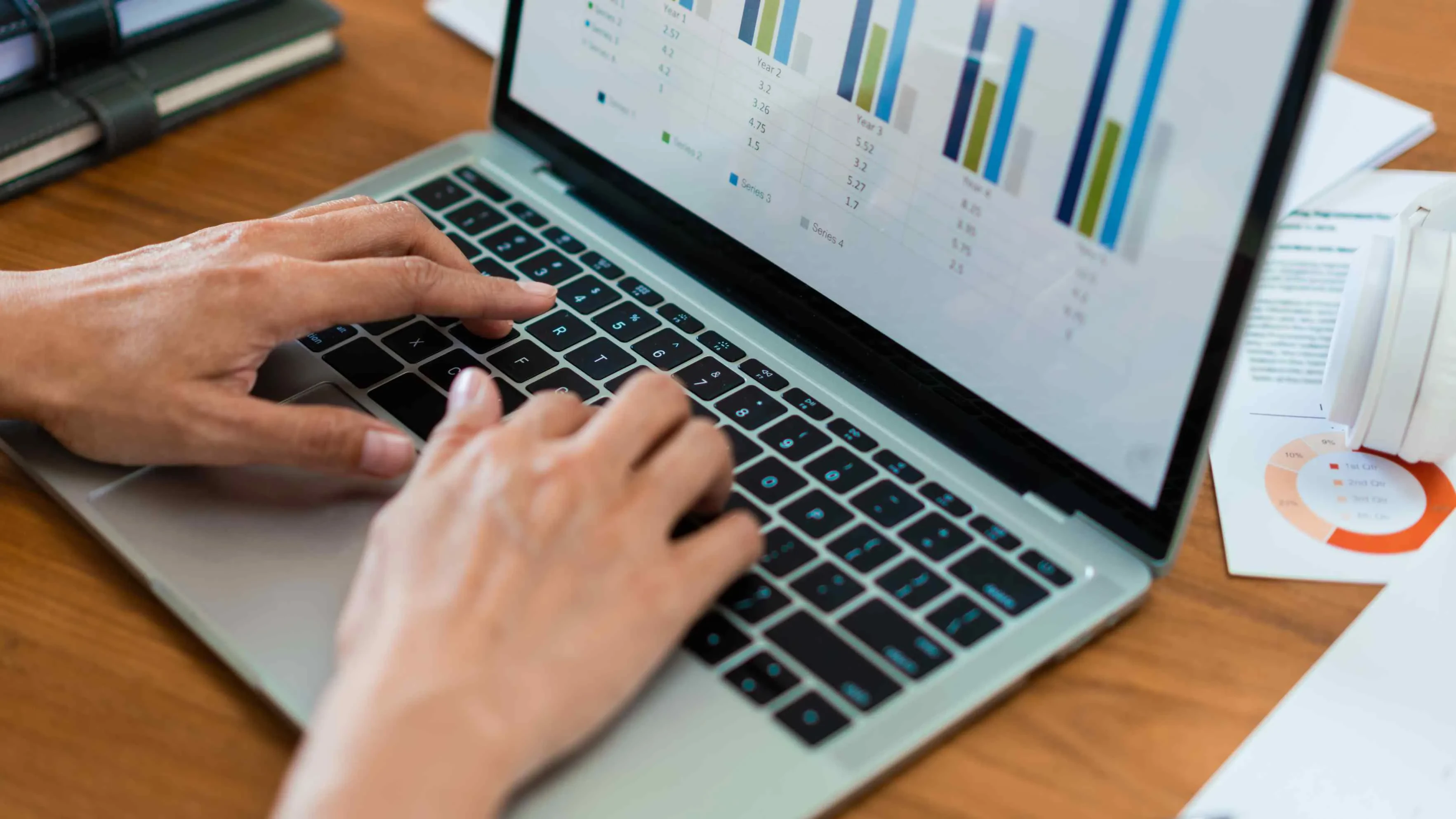 Person tippt auf Laptop mit Balkendiagramm – Symbol für datenbasierte Projektarbeit und Reporting